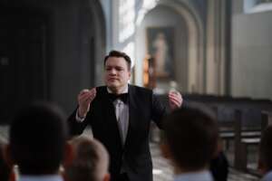 choir conductor in black suit doing hand signal